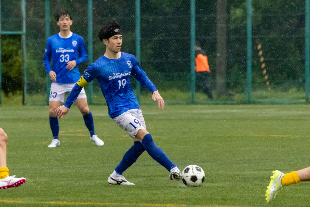 ボールを蹴る青いユニフォームの選手